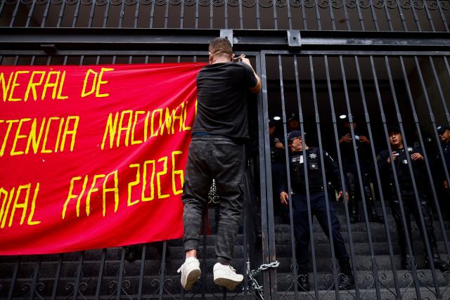 A protester hangs a banner during a demonstration by the National Coordinator of Education Workers (CNTE) ahead of the start of the 2026 FIFA World Cup outside of the Interior Ministry building in Mexico City, on June 10, 2026. (Photo by Rodrigo Oropeza / AFP)