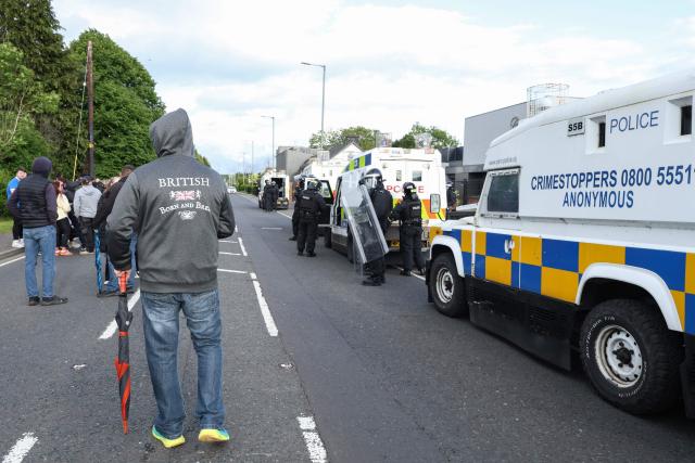 Police in riot gear seal off the road leading to a hotel previously believed to house migrants, in the town of Mallusk, Co Antrim, north of Belfast, Northern Ireland, on June 10, 2026. Northern Ireland braced on June 10 for a potential second night of violence directed at immigrants, following unrest that UK authorities say was stoked by far-right activists on social media after a brutal Belfast stabbing. (Photo by Paul Faith / AFP)