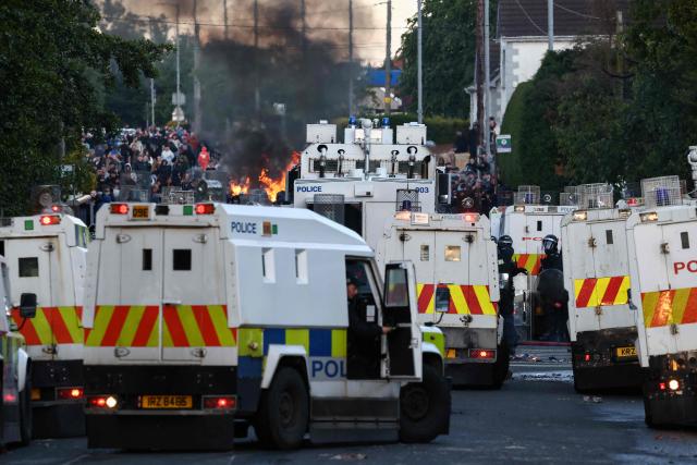 Police block the road from protesters (behind) as they gather near a hotel previously believed to house migrants, in the town of Mallusk, Co Antrim, north of Belfast, Northern Ireland, on June 10, 2026. Northern Ireland braced on June 10 for a potential second night of violence directed at immigrants, following unrest that UK authorities say was stoked by far-right activists on social media after a brutal Belfast stabbing. (Photo by Henry NICHOLLS / AFP)