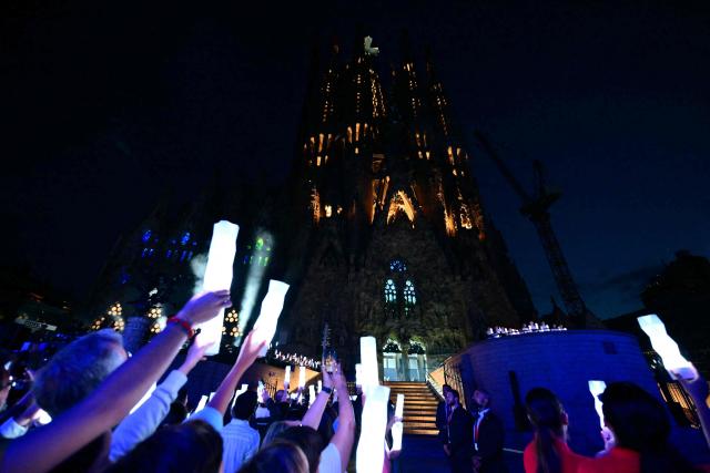 Attendees hold lights during the inauguration of the Jesus Christ tower by Pope Leo XIV, outside of the Basilica of the Sagrada Familia, in Barcelona, on June 10, 2026. Pope Leo XIV is visiting Spain June 6-12 with stops in Madrid, Barcelona, and the Canary Islands, where he will meet with migrants and organisations dedicated to helping them. (Photo by Stefano RELLANDINI / AFP)
