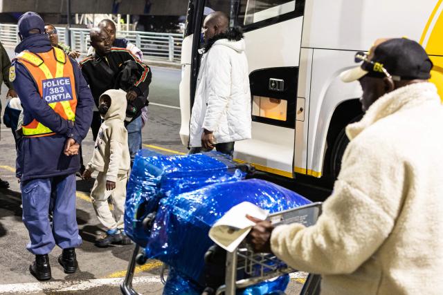 A Nigerian child looks up at a South African Police service (SAPS) officer as he and his family are directed to the entrance of the OR Tambo International Airport, in Johannesburg on June 10, 2026, to be part of the first group of Nigerian nationals to board an evacuation flight for Lagos. The first batch of Nigerian nationals board an Air Peace Airlines evacuation flight chartered by the Federal Government of Nigeria, departing for Lagos amid a wave of xenophobic attacks in South Africa. Hundreds of anti-migrant protesters marched through a township outside Johannesburg on June 8, 2026, a day after South African President Cyril Ramaphosa pledged action against groups accused of fuelling xenophobic violence. South Africa has seen recurring bouts of anti-migrant violence, with protests intensifying this year after vigilante groups ordered undocumented foreigners to leave by June 30. (Photo by EMMANUEL CROSET / AFP)