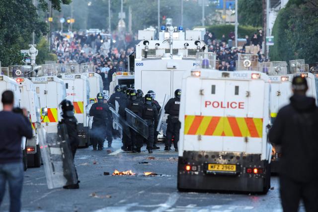 Police block the road from protesters (behind) leading to a hotel previously believed to house migrants, in Glengormley, north of Belfast, Northern Ireland, on June 10, 2026. Northern Ireland braced on June 10 for a potential second night of violence directed at immigrants, following unrest that UK authorities say was stoked by far-right activists on social media after a brutal Belfast stabbing. (Photo by Paul Faith / AFP)