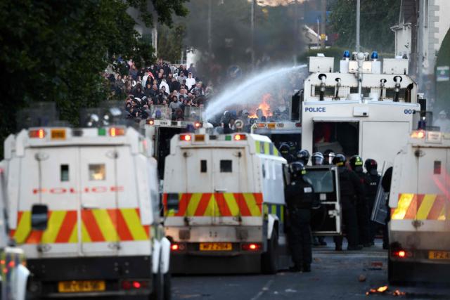 Police use water cannon as they block the road from protesters (behind) leading to a hotel previously believed to house migrants, in Glengormley, north of Belfast, Northern Ireland, on June 10, 2026. Northern Ireland braced on June 10 for a potential second night of violence directed at immigrants, following unrest that UK authorities say was stoked by far-right activists on social media after a brutal Belfast stabbing. (Photo by Henry NICHOLLS / AFP)