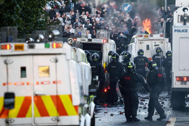 Police block the road from protesters (behind) leading to a hotel previously believed to house migrants, in Glengormley, north of Belfast, Northern Ireland, on June 10, 2026. Northern Ireland braced on June 10 for a potential second night of violence directed at immigrants, following unrest that UK authorities say was stoked by far-right activists on social media after a brutal Belfast stabbing. (Photo by Henry NICHOLLS / AFP)