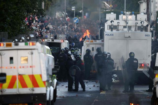 Police block the road from protesters (behind) leading to a hotel previously believed to house migrants, in Glengormley, north of Belfast, Northern Ireland, on June 10, 2026. Northern Ireland braced on June 10 for a potential second night of violence directed at immigrants, following unrest that UK authorities say was stoked by far-right activists on social media after a brutal Belfast stabbing. (Photo by Henry NICHOLLS / AFP)