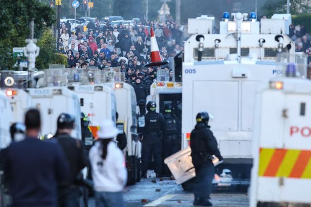 A traffic cone (C) is hurled toward police as they block the road from protesters leading to a hotel previously believed to house migrants, in Glengormley, north of Belfast, Northern Ireland, on June 10, 2026. Northern Ireland braced on June 10 for a potential second night of violence directed at immigrants, following unrest that UK authorities say was stoked by far-right activists on social media after a brutal Belfast stabbing. (Photo by Paul Faith / AFP)