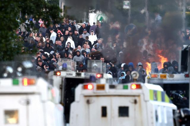 Police block the road from protesters (behind) leading to a hotel previously believed to house migrants, in Glengormley, north of Belfast, Northern Ireland, on June 10, 2026. Northern Ireland braced on June 10 for a potential second night of violence directed at immigrants, following unrest that UK authorities say was stoked by far-right activists on social media after a brutal Belfast stabbing. (Photo by Henry NICHOLLS / AFP)