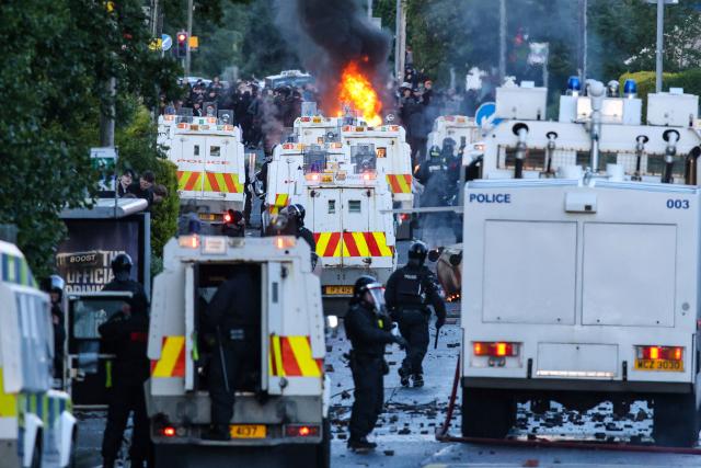 Fires burn as police block the road from protesters (behind) leading to a hotel previously believed to house migrants, in Glengormley, north of Belfast, Northern Ireland, on June 10, 2026. Northern Ireland braced on June 10 for a potential second night of violence directed at immigrants, following unrest that UK authorities say was stoked by far-right activists on social media after a brutal Belfast stabbing. (Photo by Paul Faith / AFP)