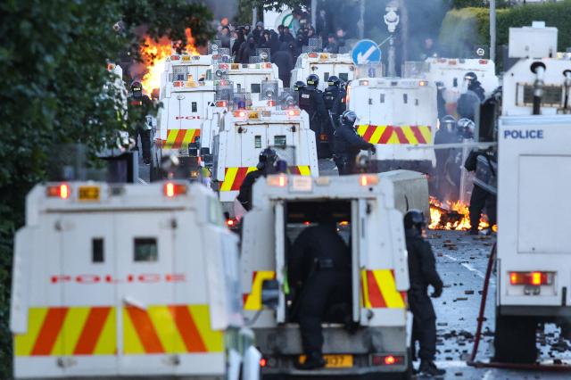Fires burn as police block the road from protesters leading to a hotel previously believed to house migrants, in Glengormley, north of Belfast, Northern Ireland, on June 10, 2026. Northern Ireland braced on June 10 for a potential second night of violence directed at immigrants, following unrest that UK authorities say was stoked by far-right activists on social media after a brutal Belfast stabbing. (Photo by Paul Faith / AFP)