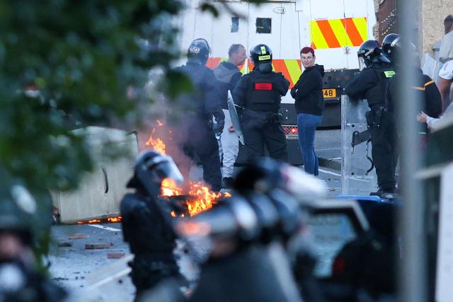 Police gather behind lines as they hold off protesters in Glengormley, north of Belfast, Northern Ireland, on June 10, 2026. Police used water cannon late on June 10 to disperse small crowds who had gathered for a second night in Northern Ireland as UK authorities blamed far-right activists for stoking anger on social media following a brutal stabbing. (Photo by Paul Faith / AFP)