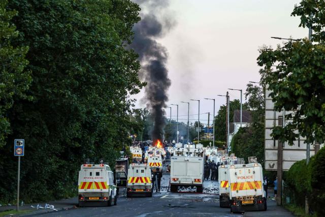 Smoke rises as protesters stand off with police in Glengormley, north of Belfast, Northern Ireland, on June 10, 2026. Police used water cannon late on June 10 to disperse small crowds who had gathered for a second night in Northern Ireland as UK authorities blamed far-right activists for stoking anger on social media following a brutal stabbing. (Photo by Henry NICHOLLS / AFP)