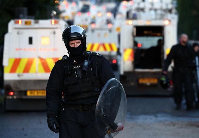 Police in riot gear work behind their blockade with protestors, holding them from reaching a hotel previously believed to house migrants, in Glengormley, north of Belfast, Northern Ireland, on June 10, 2026. Northern Ireland braced on June 10 for a potential second night of violence directed at immigrants, following unrest that UK authorities say was stoked by far-right activists on social media after a brutal Belfast stabbing. (Photo by Henry NICHOLLS / AFP)