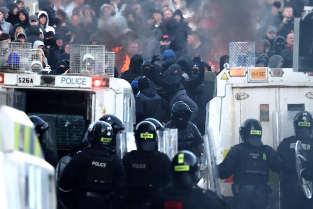 Protesters (behind) stand off with police on Antrim Road in Glengormley, north of Belfast, Northern Ireland, on June 10, 2026. Police used water cannons late on June 10 to disperse small crowds who had gathered for a second night in Northern Ireland as UK authorities blamed far-right activists for stoking anger on social media following a brutal stabbing. (Photo by Henry NICHOLLS / AFP)