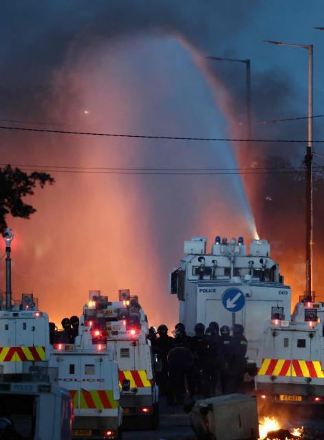 Police use water cannon as they block the road from protesters (behind) leading to a hotel previously believed to house migrants, an Atrim Road in Glengormley, north of Belfast, Northern Ireland, on June 10, 2026. Police used water cannons late on June 10 to disperse small crowds who had gathered for a second night in Northern Ireland as UK authorities blamed far-right activists for stoking anger on social media following a brutal stabbing. (Photo by Henry NICHOLLS / AFP)