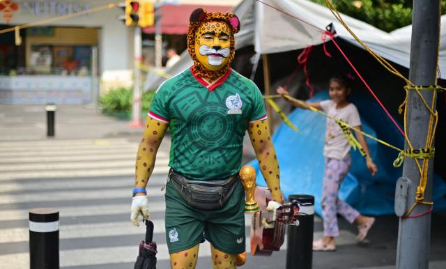 A Mexico football fan painted as a jaguar and wearing the team’s jersey walks near the Zocalo in Mexico City on June 10, 2026, one day ahead of the opening of the 2026 FIFA World Cup. (Photo by Marco Antonio MARTINEZ / AFP)