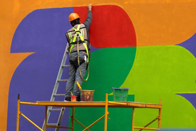 A worker paints the FIFA 2026 World Cup logo on a wall of the FIFA Fan Fest installations at Zocalo Square, one day before the opening of the 2026 FIFA World Cup football tournament in Mexico City on June 10, 2026. (Photo by Gerardo Luna / AFP)