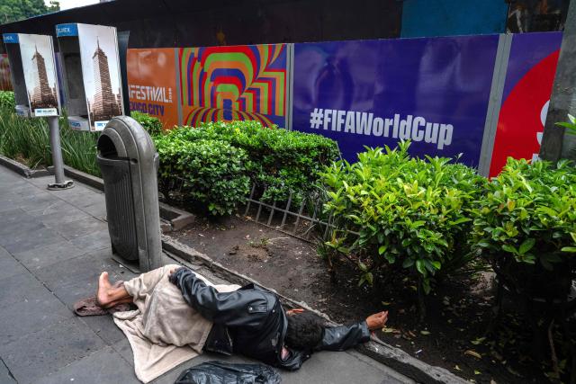 A man sleeps on a street next to fences surrounding the FIFA Fan Fest installations at Zocalo Square, one day before the opening of the 2026 FIFA World Cup football tournament in Mexico City on June 10, 2026. (Photo by Gerardo LUNA / AFP)