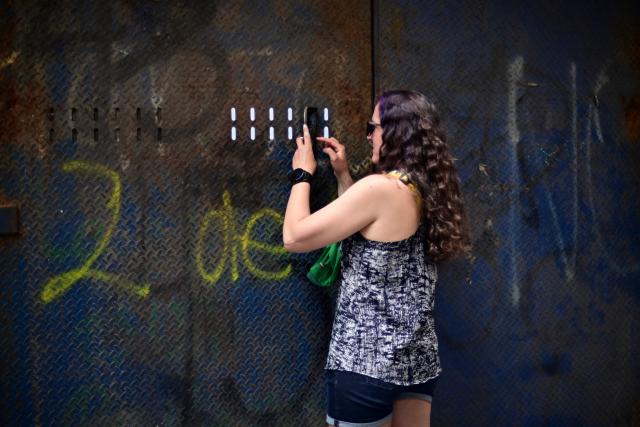 A woman takes photos through a security barrier blocking access to the Fan Fest at Mexico City's Zocalo square on June 10, 2026, amid a threatened protest by the National Coordinator of Education Workers (CNTE) ahead of the 2026 FIFA World Cup. (Photo by Marco Antonio MARTINEZ / AFP)