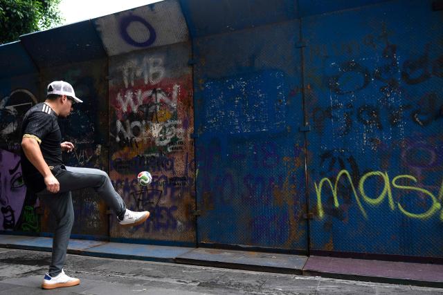A man plays with a little ball on a security barrier of the FIFA Fan Fest at Zocalo Square, one day before the opening of the 2026 FIFA World Cup football tournament in Mexico City on June 10, 2026. (Photo by Gerardo LUNA / AFP)