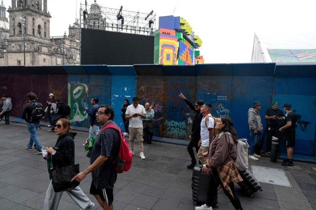 People walk past a security barrier of the FIFA Fan Fest at Zocalo Square, one day before the opening of the 2026 FIFA World Cup football tournament in Mexico City on June 10, 2026. (Photo by Gerardo Luna / AFP)