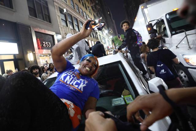 Knicks fans climb onto a car in New York, on June 10, 2026 during game four of the NBA Finals between the San Antonio Spurs and the New York Knicks. (Photo by CHARLY TRIBALLEAU / AFP)