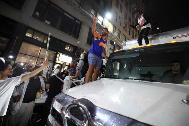 Knicks fans climb onto a truck in New York, on June 10, 2026 during game four of the NBA Finals between the San Antonio Spurs and the New York Knicks. (Photo by CHARLY TRIBALLEAU / AFP)