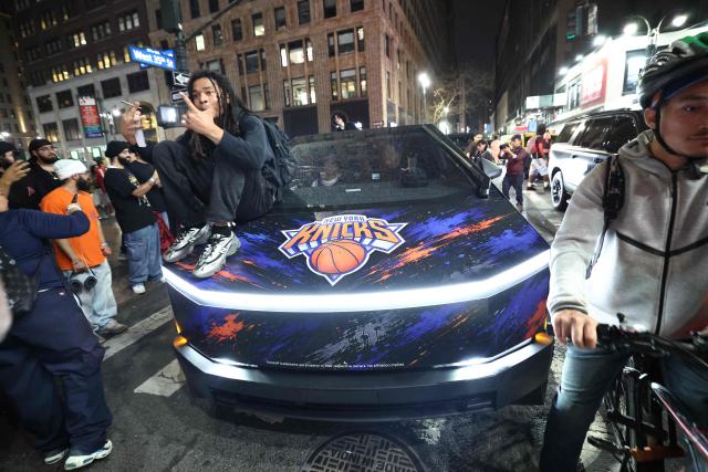 A Knicks fan sits on the hood of a car with Knicks stickers in New York, on June 10, 2026 during game four of the NBA Finals between the San Antonio Spurs and the New York Knicks. (Photo by CHARLY TRIBALLEAU / AFP)