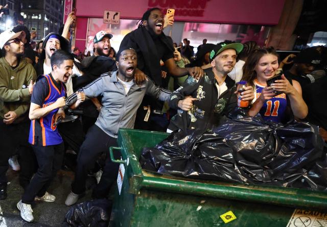 York Knicks fans gathered behind a pile of trash outside Madison Square Garden, cheer as they watch the NBA finals Game 4 of the NBA Finals between the New York Knicks and the San Antonio Spurs in New York on June 10, 2026. (Photo by CHARLY TRIBALLEAU / AFP)