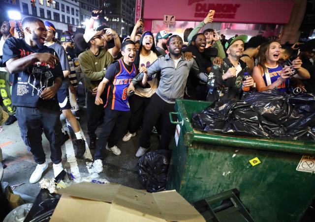 York Knicks fans gathered behind a pile of trash outside Madison Square Garden, cheer as they watch the NBA finals Game 4 of the NBA Finals between the New York Knicks and the San Antonio Spurs in New York on June 10, 2026. (Photo by CHARLY TRIBALLEAU / AFP)
