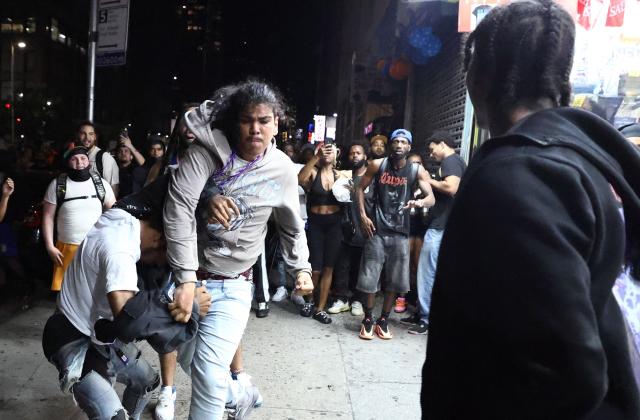 People fight in the street as New York Knicks fans celebrate outside Madison Square Garden after their team’s Game 4 victory over the San Antonio Spurs in the NBA Finals in New York on June 10, 2026. (Photo by CHARLY TRIBALLEAU / AFP)