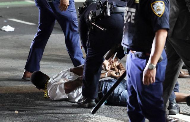 NYPD officers detain a man after New York Knicks victory celebrations turned disorderly following the team’s Game 4 win over the San Antonio Spurs in the NBA Finals in New York on June 10, 2026. (Photo by CHARLY TRIBALLEAU / AFP)