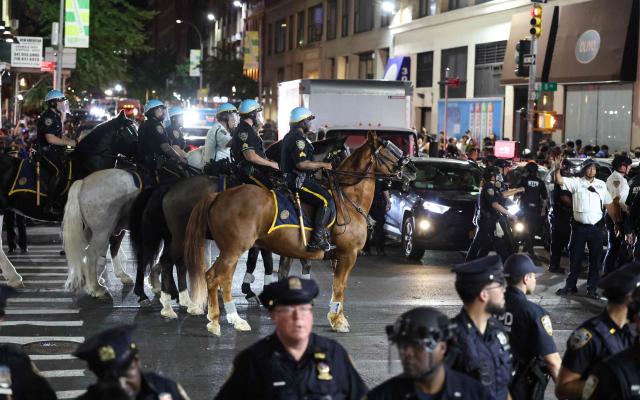 NYPD officers and mounted police attempt to disperse the crowd and secure the area after New York Knicks victory celebrations turned disorderly following the team’s Game 4 win over the San Antonio Spurs in the NBA Finals in New York on June 10, 2026. (Photo by CHARLY TRIBALLEAU / AFP)