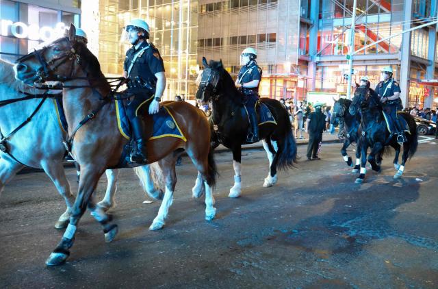 NYPD mounted police officers arrive as reinforcements after New York Knicks victory celebrations turned disorderly following the team’s Game 4 win over the San Antonio Spurs in the NBA Finals in New York on June 10, 2026. (Photo by CHARLY TRIBALLEAU / AFP)