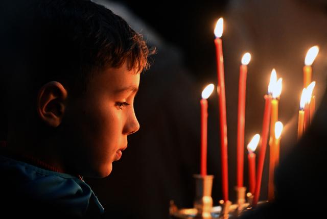 A Russian Orthodox believer prays during a service at the Pskovo-Pechersky monastery in the town of Pechory, some 50 kilometres outside Pskov, on April 19, 2026. (Photo by Olga MALTSEVA / AFP)