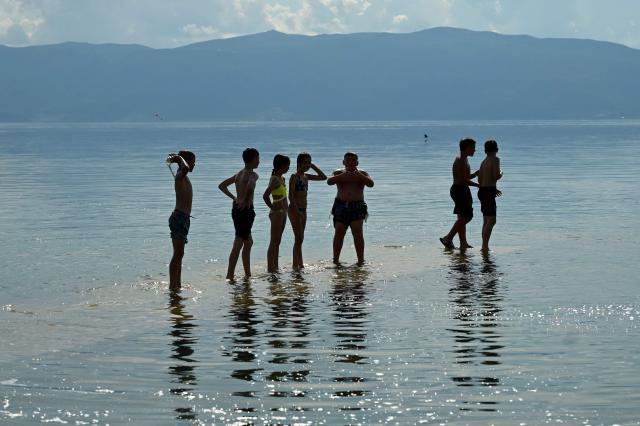 Children wade in the waters of Lake Ohrid to cool off on a warm day in the village of Pestani, near Ohrid, on June 10, 2026. (Photo by Robert ATANASOVSKI / AFP)