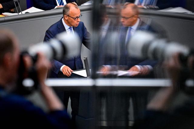A news photographer photographs German Chancellor Friedrich Merz delivering a speach at the German Bundestag (lower house of parliament) on June 11, 2026, ahead of an EU summit. (Photo by John MACDOUGALL / AFP)