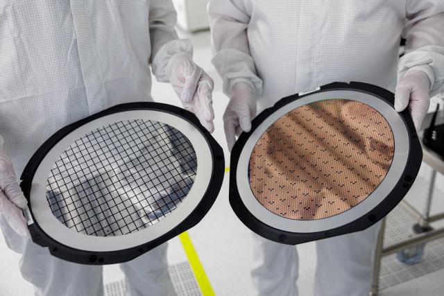 Employees hold two 300mm wafer at the new Smart Power Fab of German semiconductor manufacturer Infineon Technologies AG in Dresden, eastern Germany, on June 10, 2026. On July 2, 2026, Infineon will officially open its Smart Power Fab that manufactures power semiconductors as well as analog/mixed-signal-components in Dresden. With an investment of five billion euros, the new facility represents the largest single investment in Infineon's history. (Photo by Jens SCHLÜTER / AFP)