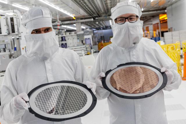 Employees hold two 300mm wafer at the new Smart Power Fab of German semiconductor manufacturer Infineon Technologies AG in Dresden, eastern Germany, on June 10, 2026. On July 2, 2026, Infineon will officially open its Smart Power Fab that manufactures power semiconductors as well as analog/mixed-signal-components in Dresden. With an investment of five billion euros, the new facility represents the largest single investment in Infineon's history. (Photo by Jens SCHLÜTER / AFP)