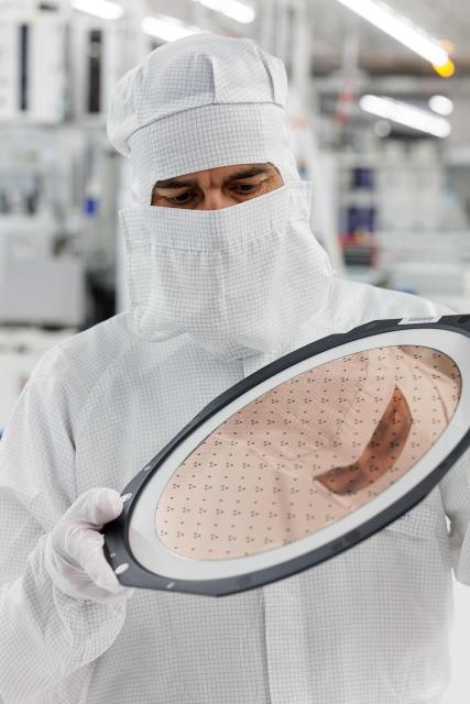 An employee holds a 300mm wafer at the new Smart Power Fab of German semiconductor manufacturer Infineon Technologies AG in Dresden, eastern Germany, on June 10, 2026. On July 2, 2026, Infineon will officially open its Smart Power Fab that manufactures power semiconductors as well as analog/mixed-signal-components in Dresden. With an investment of five billion euros, the new facility represents the largest single investment in Infineon's history. (Photo by Jens SCHLÜTER / AFP)