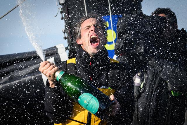 (FILES) French skipper Charlie Dalin celebrates with champagne after arriving at the harbour after winning the 10th edition of the Vendee Globe around the world monohull solo sailing race, in Les Sables-d'Olonne, western France, early on January 14, 2025. French offshore sailor and Vendee Globe 2024/2025 winner Charlie Dalin has died in Quimper, western France, aged 42, from cancer, his family announced on June 11, 2026. (Photo by Loic VENANCE / AFP)