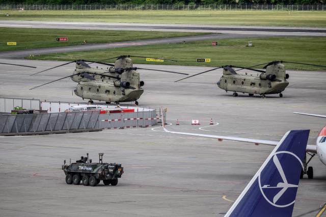 An armoured vehicle of the Swiss police passes in front of CH-47F Chinook helicopter of the US Army during a patrol on the tarmac at Geneva Airport ahead of the upcoming G7 summit in nearby Evian, in Geneva, on June 11, 2026. (Photo by Fabrice COFFRINI / AFP)