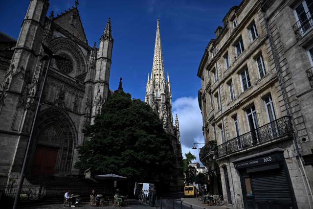 People sit at the terrasse of a cafe near the restored Saint-Michel bell tower (C) in Bordeaux, southwestern France on June 11, 2026. The 114-meter high Saint-Michel, built at the end of the 15th century, is set to reopen to the public on June 13 following five years of restoration. (Photo by Christophe ARCHAMBAULT / AFP)