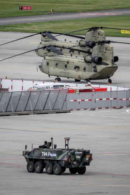 An armoured vehicle of the Swiss police passes in front of CH-47F Chinook helicopter of the US Army during a patrol on the tarmac at Geneva Airport ahead of the upcoming G7 summit in nearby Evian, in Geneva on June 11, 2026. (Photo by Fabrice COFFRINI / AFP)