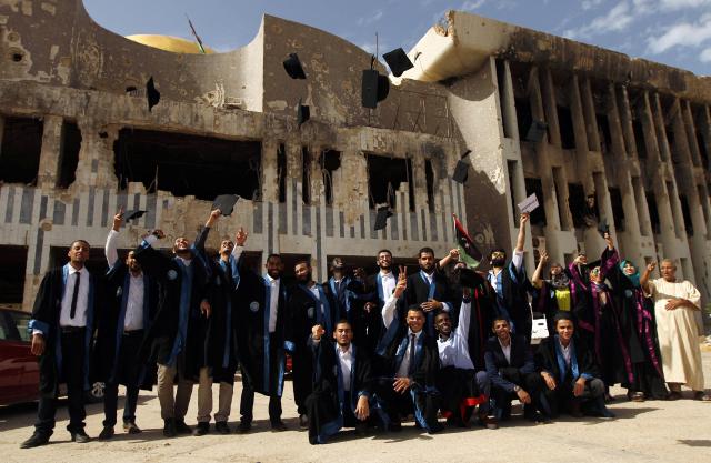 (FILES) Students from the chemical engineering department of Benghazi University throw their hats in the air as they celebrate on October 24, 2016, during their graduation ceremony in front of a building of the university that was destroyed due to fighting. A decade after fierce battles reduced much of the University of Benghazi to rubble, students at Libya's oldest and largest university are once again looking to the future with optimism. The university, founded in 1955, had become after the 2011 uprisings that toppled and killed longtime ruler Muammar Gaddafi the stage of intense fightings between jihadist groups and forces led by military strongman Khalifa Haftar. (Photo by Abdullah DOMA / AFP) / To go with 'Libya-Youth-Development-Education', REPORTAGE by Françoise KADRI