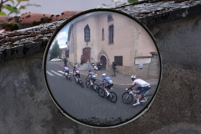This photograph shows a traffic mirror reflecting riders cycling during the 5th stage of the Tour Auvergne-Rhone-Alpes cycling race (formerly known as the Criterium du Dauphine), 195,8km between Saint-Chamond and Villars-les-Dombes, central France, on June 11, 2026. (Photo by Anne-Christine POUJOULAT / AFP)