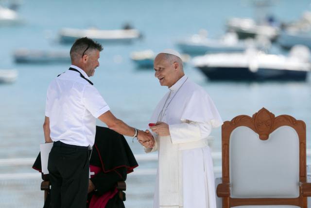 Pope Leo XIV shakes hands with a senior official from Spain's Maritime Rescue service during a meeting with organizations working with migrants in the port of Arguineguin on the Canary Island of Gran Canaria, a place accustomed to the arrival of migrants, on June 11, 2026. Pope Leo XIV is visiting Spain June 6-12 with stops in Madrid, Barcelona, and the Canary Islands, where he will meet with migrants and organisations dedicated to helping them. (Photo by Pierre-Philippe MARCOU / AFP)