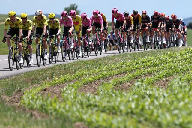The pack of riders including Team Visma - Lease a Bike (L), EF Education - EasyPost (C) and Tudor Pro Cycling riders cycles during the 5th stage of the Tour Auvergne-Rhone-Alpes cycling race (formerly known as the Criterium du Dauphine), 195,8km between Saint-Chamond and Villars-les-Dombes, central France, on June 11, 2026. (Photo by Anne-Christine POUJOULAT / AFP)