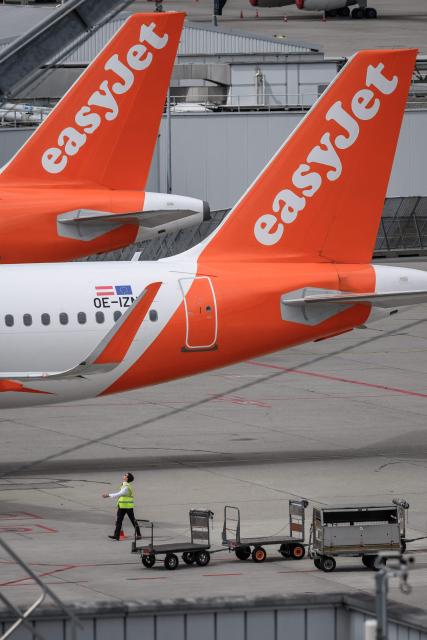 A staff looks on beneath of the tails of Easyjet aircrafts at Geneva Airport on June 11, 2026. British no-frills airline EasyJet denounced as "opportunistic" a possible takeover bid from a US private equity firm. Castlelake, which owns 2.14 percent of EasyJet, revealed on May 29, 2026 that it was considering an offer for the carrier, which operates mainly across Europe. (Photo by Fabrice COFFRINI / AFP)