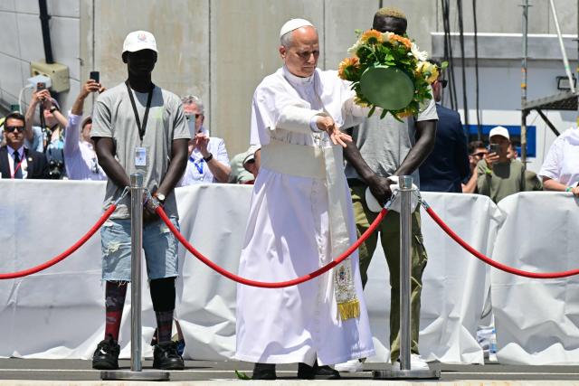 Pope Leo XIV, flanked by two migrants, throws a wreath to the sea to remember all the migrants who perished during their journey, at the Port of Arguineguin on the Canary Island of Gran Canaria, a place accustomed to the arrival of migrants, on June 11, 2026. Pope Leo XIV is visiting Spain June 6-12 with stops in Madrid, Barcelona, and the Canary Islands, where he will meet with migrants and organisations dedicated to helping them. (Photo by Stefano RELLANDINI / AFP)