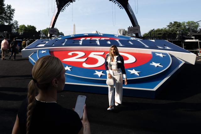 A woman poses by a "UFC Freedom 250" logo and the structure, known as "The Claw," for the upcoming UFC fight that US President Donald Trump will host as part of the 250th anniversary of the United States is seen on the South Lawn of the White House during a media preview in Washington, DC, June 11, 2026. The Ultimate Fighting Championship (UFC) event will be held on US President Donald Trump's 80th birthday on June 14. (Photo by SAUL LOEB / AFP)